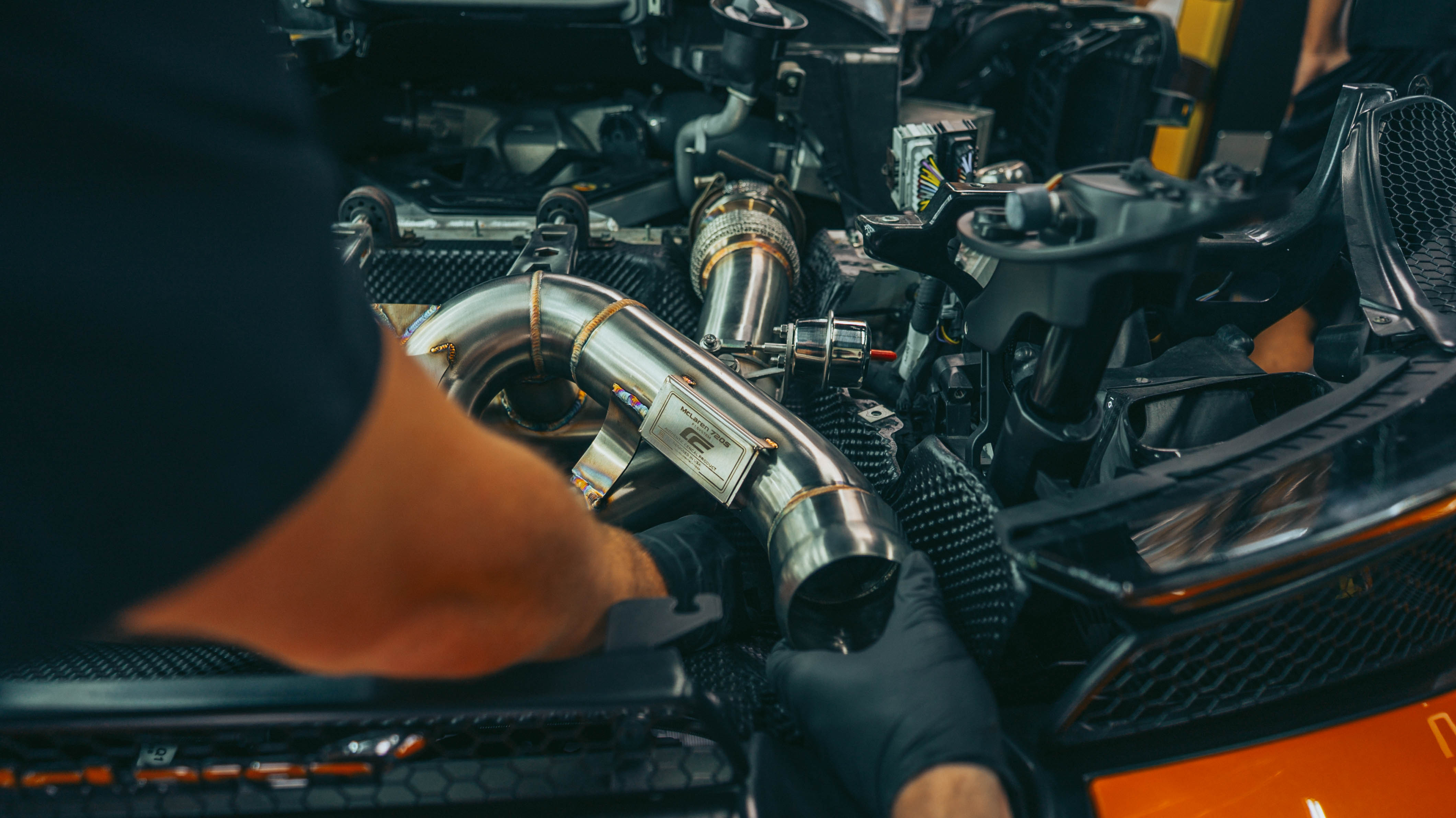 McLaren 720S exhaust system layout on workshop floor with vehicle